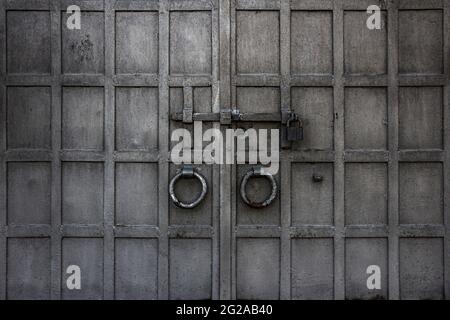Ein altes schmiedeeisernem Tor mit Griff, Türklopfen, Riegel, kann als Hintergrund verwendet werden Stockfoto