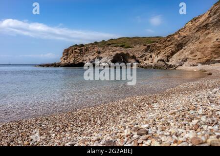 Wilder mediterraner Kiesstrand aus nächster Nähe mit felsigen Klippen und blauem klarem Wasser. Reisen Sie nach Griechenland in der Nähe von Athen. Sommer Natur szenische Lagune Stockfoto