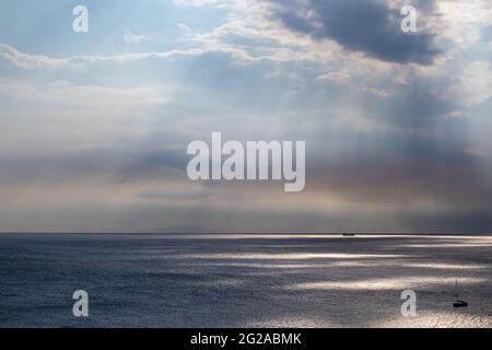 Sonnenstrahlen, die durch Wolken über dem Meer in Griechenland scheinen. Dramatische Wolkenlandschaft auf der wasseroberfläche des mittelmeers Stockfoto