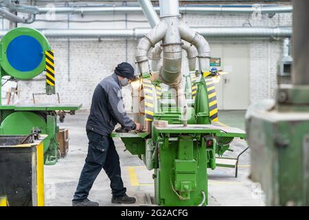 Unkenntlich Arbeiter Maske in Holz Werkstatt arbeitet mit großen Schleifmaschine Werkzeug in Holzbearbeitungsanlage Innenraum. Stockfoto