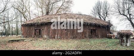 Altes Ziegelgebäude mit überwucherten Wänden, Gras und Moos auf dem Dach, verlassene Struktur Stockfoto