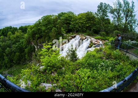 Chittenango, New York - 30. Mai 2021: Eine flächendeckende, ultraweite Ansicht des Hauptwasserfalls der Chittenango Falls im Upstate New York mit zwei reifen Liebhabern Stockfoto