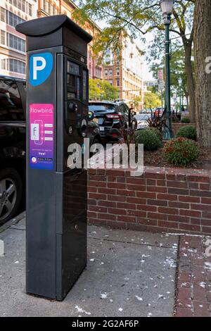 Syracuse, New York - 25. September 2020: Parkscheinautomat identifiziert durch den Buchstaben P mit geparkten Autos im Hintergrund. Stockfoto