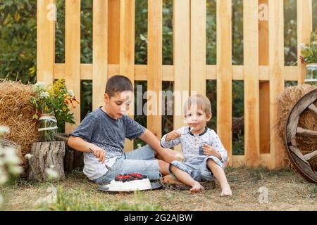 Abenteuerzeit. Zwei niedliche Jungen essen gerne gesunde Lebensmittel im Freien. Stockfoto