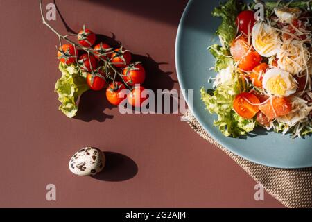 Auf dem Tisch stehen zwei Teller mit Salat, Wachteleiern und Kirschtomaten Stockfoto