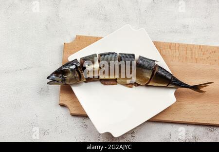 Scheiben geräucherter Fischmakrele auf einem weißen rechteckigen Teller auf hellgrauem Hintergrund. Draufsicht, flach liegend Stockfoto
