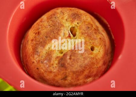 Gebackene Muffins mit sonnengetrockneten Tomaten in Silikonform nach dem Backen Stockfoto