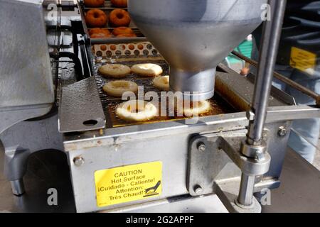 Eine automatische Donut-Maschine zur Herstellung frischer Apfelmost-Donuts auf einem Wochenend-Bauernmarkt auf dem Rittenhouse Square in Philadelphia. Stockfoto