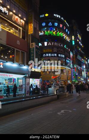 Busan, Südkorea - 23. März 2018: Nächtlicher Blick auf die Straße mit farbenfroher Werbebeleuchtung gehen die Menschen auf der Straße in der Innenstadt von Busan CI Stockfoto