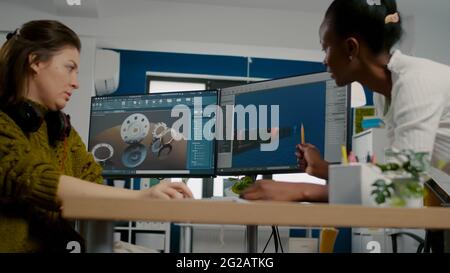 Diverse Frauen Spiel Software-Entwickler erstellen Spiel-Schnittstelle sitzen in Startup-Kreativagentur Unternehmen mit pc mit zwei Displays. Mitarbeiter, die Online-Videospiele mit moderner Technologie entwickeln Stockfoto