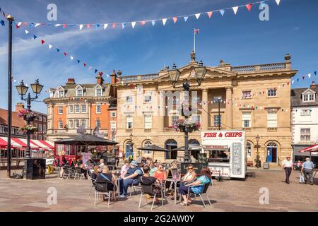 4. Juli 2019: Newark on Trent, Nottinghamshire, Großbritannien - Menschen trinken Kaffee in einem Café auf dem historischen Marktplatz, mit dem Rathaus hinter sich. Stockfoto
