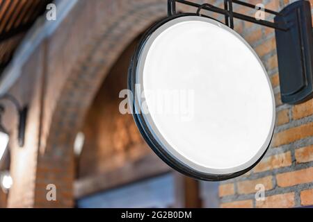Der Circle White Lightbox hat an der Wand vor dem Backsteinpfosten in einem Tungsten Ambient Umgebung Vintage Shopping Community Mall gehängt. Stockfoto