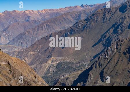 Landschaftlich schöner Blick auf den Colca Canyon, Peru, mit Wanderwegen und einem in der Ferne sichtbaren Dorf am Rande der Klippen Stockfoto