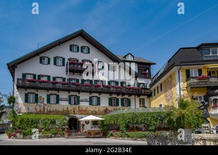 HALLSTAT, ÖSTERREICH - 08. Jan 2021: Typisch österreichisches Alpenhaus mit hellen Blumen auf dem Balkon Stockfoto