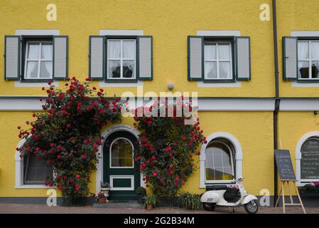 HALLSTAT, ÖSTERREICH - 08. Jan 2021: Typisch österreichisches Alpenhaus mit hellen Blumen auf dem Balkon Stockfoto