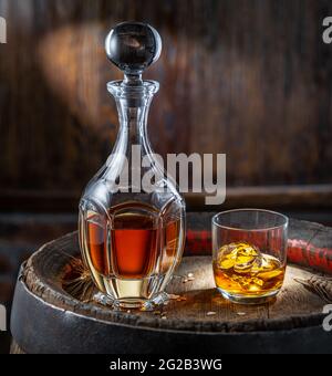 Karaffe Whisky und Glas Whisky auf altem Holzfass auf dunklem Hintergrund. Stockfoto