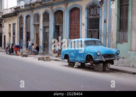 Havanna, Kuba - 19. November 2005: Straßenszene in Zentral-Havanna, als ein Mechaniker ein Motorrad auf der Straße repariert, auf dem ein zerschlagenes Oldtimer ruht Stockfoto