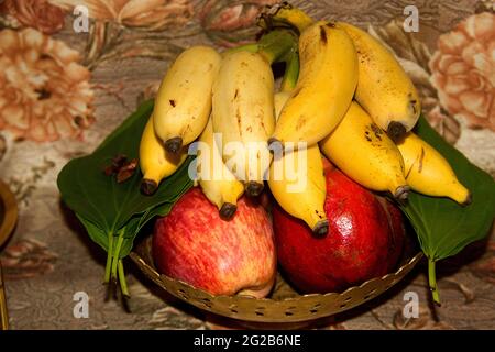 Angebot von Banane, Apfel, Granatapfel, Betelblätter, Betelnuss in Messingschale gelegt Stockfoto