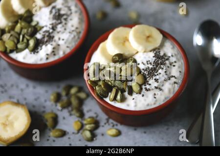 Schalen mit Chia-Pudding mit Bananen- und Kürbiskernen. Stockfoto