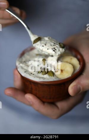 Gesunder Chia-Joghurt mit Samen und Banane in den Händen. Stockfoto