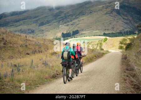 Drei Personen fahren nacheinander auf dem Otago Central Rail Trail in Richtung Middlemarch, South Island, Neuseeland Stockfoto