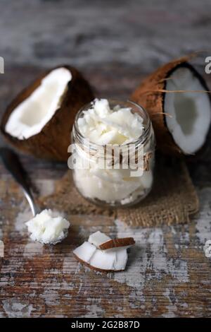 Kokosöl in einem Glas. Kokosnusshälften. Stockfoto