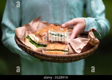 Korb mit hausgemachten vegetarischen Sandwiches mit Fladenbrot, Käse-Dip und frischen Bärlauch-Blättern in den Händen des Mädchens. Stockfoto