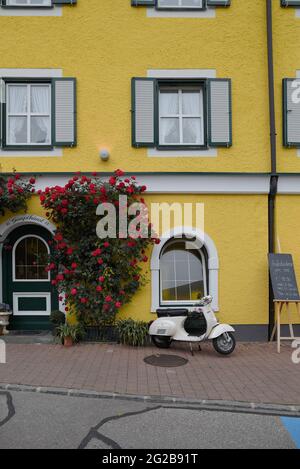 HALLSTAT, ÖSTERREICH - 08. Jan 2021: Typisch österreichisches Alpenhaus mit hellen Blumen auf dem Balkon Stockfoto