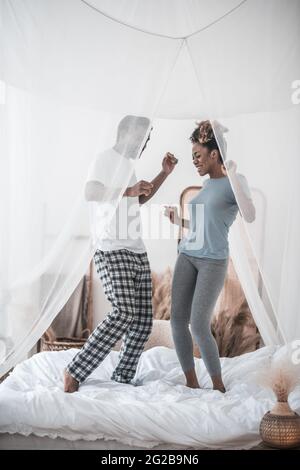Mann und Frau tanzen morgens auf dem Bett Stockfoto