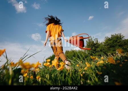 Das Mädchen läuft glücklich durch das Feld gelbe Blumen im Park. Stockfoto