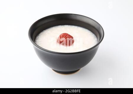 Reisbrei mit Salz eingelegten Pflaumen in einer Schüssel isoliert auf weißem Hintergrund Stockfoto