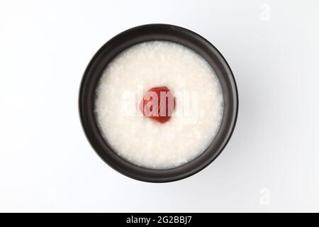 Reisbrei mit Salz eingelegten Pflaumen in einer Schüssel isoliert auf weißem Hintergrund Stockfoto