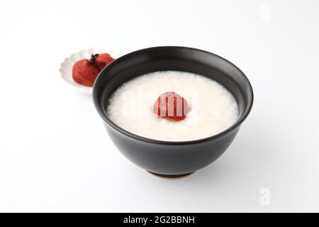 Reisbrei mit Salz eingelegten Pflaumen in einer Schüssel isoliert auf weißem Hintergrund Stockfoto