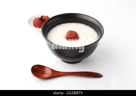 Reisbrei mit Salz eingelegten Pflaumen in einer Schüssel isoliert auf weißem Hintergrund Stockfoto