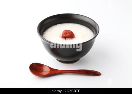 Reisbrei mit Salz eingelegten Pflaumen in einer Schüssel isoliert auf weißem Hintergrund Stockfoto