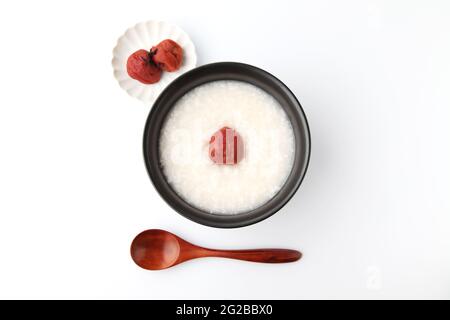 Reisbrei mit Salz eingelegten Pflaumen in einer Schüssel isoliert auf weißem Hintergrund Stockfoto