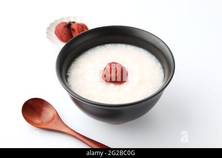 Reisbrei mit Salz eingelegten Pflaumen in einer Schüssel isoliert auf weißem Hintergrund Stockfoto