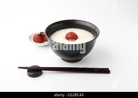 Reisbrei mit salzeingelegter Pflaume in Essstäbchen, isoliert auf weißem Hintergrund Stockfoto