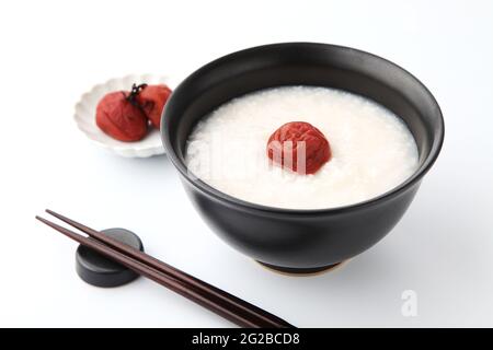 Reisbrei mit salzeingelegter Pflaume in Essstäbchen, isoliert auf weißem Hintergrund Stockfoto