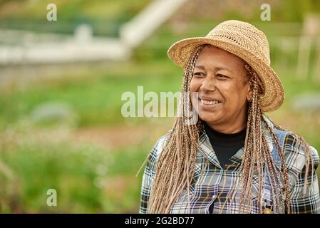 Lächelnder ethnischer Bauer im Strohhut auf der Plantage Stockfoto