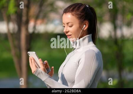 Foto einer jungen Frau mit einem Smartphone. Sie wählt Joggingmusik. Fit halten und gesund Lebensstil Konzept. Stockfoto