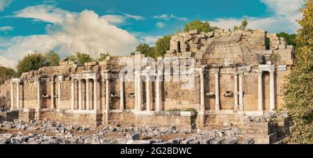 Panoramablick auf die Ruinen der Säulen des Nymphaeum-Brunnens in der alten Seite in Manavgat County während des Sonnenuntergangs. Kulturtourismus Reiseziel. Stockfoto