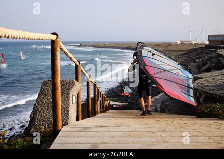 Windsurfer geht zum Wasser, um sein Surfbrett zu segeln Stockfoto