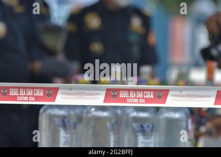 Palu, Indonesien. Juni 2021. Zollbänder, die von Beamten während der Zerstörung illegaler Waren zur Strafverfolgung im Jahr 2020 installiert werden. Insgesamt wurden 1,157 Flaschen Alkohol, 162,321 Zigaretten und 115 Flaschen anderer Tabakverarbeitungserzeugnisse oder Flüssigvapes durch den Palu-Zoll durch unsachgemäßes Anbringen von Verbrauchsbändern zerstört. (Foto: Adi Pranata/Pacific Press) Quelle: Pacific Press Media Production Corp./Alamy Live News Stockfoto