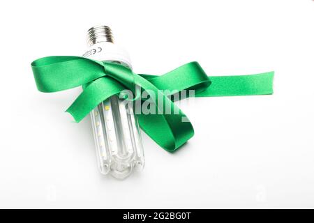 Umweltfreundliche Glühbirne mit grünem Band als Geschenk, spart Energie und Geld. LED-Lampe, energiesparend. Ein gutes Geschenk ist grüne und ökologische Energie. Stockfoto