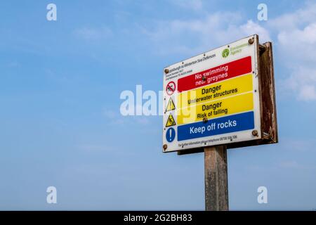 Ein Schild am Strand von Horsey Bay warnt Schwimmer davor, in der Nähe der Groynes zu schwimmen. Stockfoto