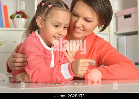 Mutter und Tochter legen Münzen in Sparschwein Stockfoto