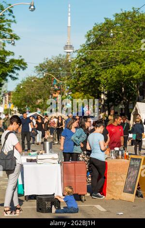 Menschen an einem kleinen Imbissstand beim Dundas West Festival 2015 in Little Portugal, im Hintergrund der CN Tower. Dundas West Festival ist ein jährliches fe Stockfoto