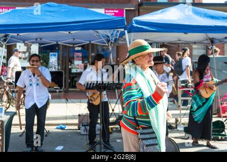 Eine alte Dame, die im Salsa auf der St. Clair Ave West tanzt, mit einer Band von Musikern, die im Hintergrund Musik spielen. Die Dame trägt einen Hut und Th Stockfoto
