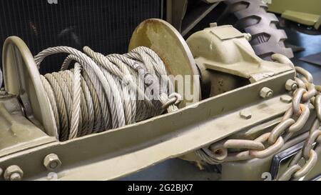 Ein detailliertes Foto einer mechanischen Winde mit einem Kabel. Ein rostig altes Abschleppseil, das an einem schweren Militärfahrzeug befestigt ist Stockfoto